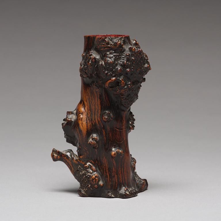 A Chinese wooden brush pot in the shape of a tree trunk.