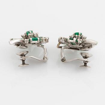 455. A pair of 14K white gold, emerald and round brilliant- and baguette cut diamond ear clips.