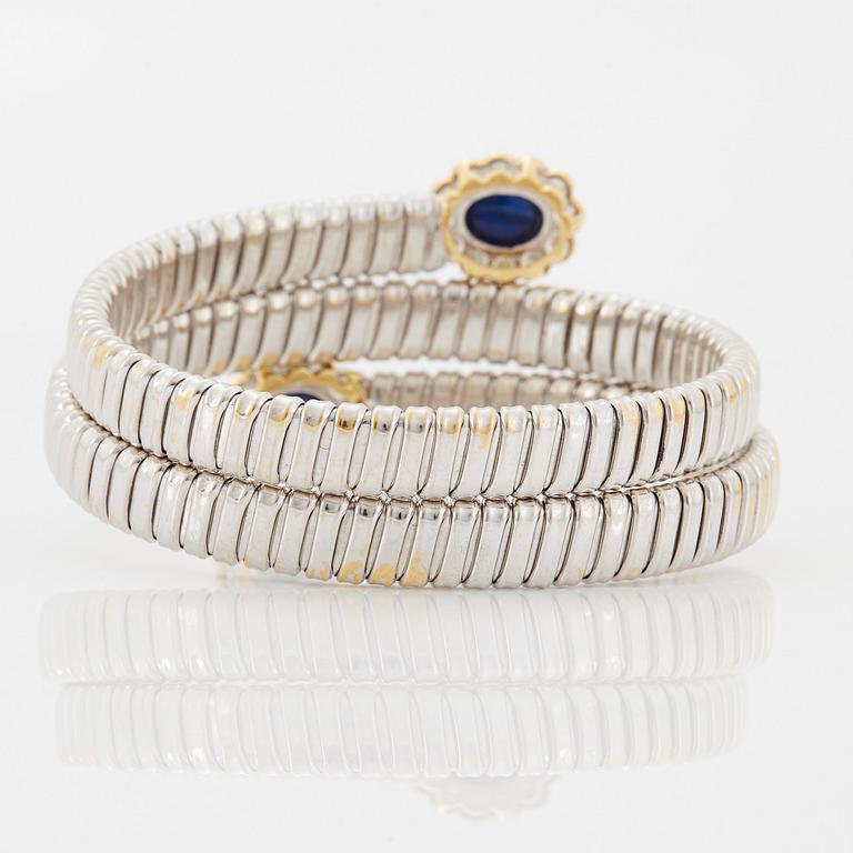 An 18K gold bangle set with cabochon-cut sapphires and round brilliant-cut diamonds.