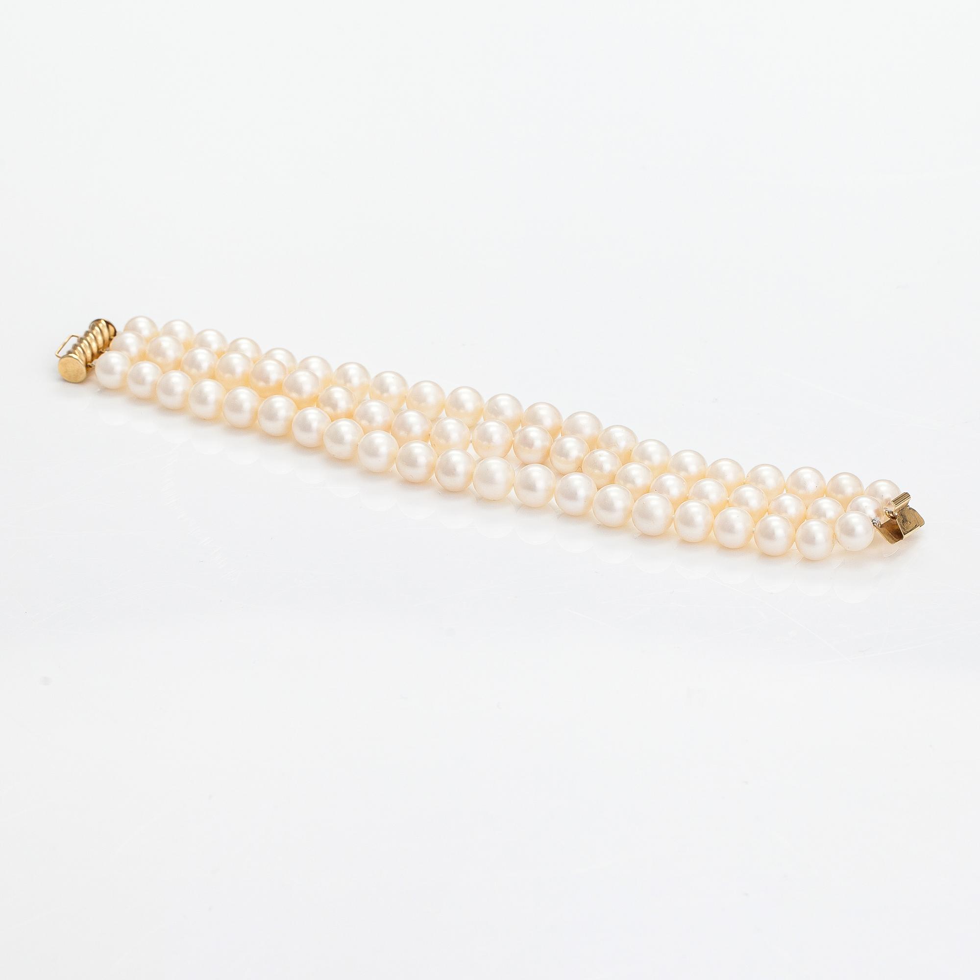 A three-strand pearl bracelet with cultured pearls and a 14K gold clasp.