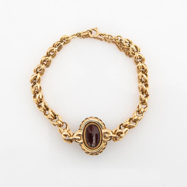 Bracelet in 18K gold set with rose-cut diamonds and an oval cabochon-cut garnet.
