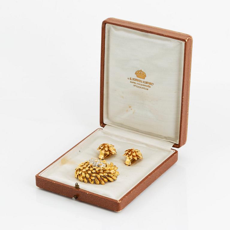 An 18K gold brooch set with round brilliant-cut diamonds and a pair of 18K gold earrings.