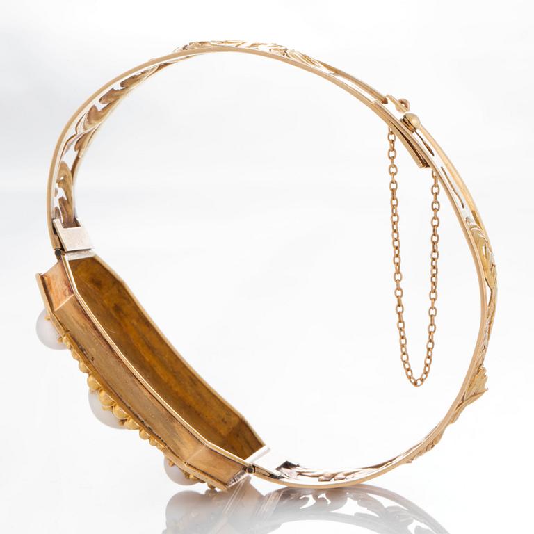 An 18K gold bracelet set with three pearls.