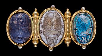 884. Brooch set with three carved and glazed steatite or ceramic scarab amulets, 1860's.
