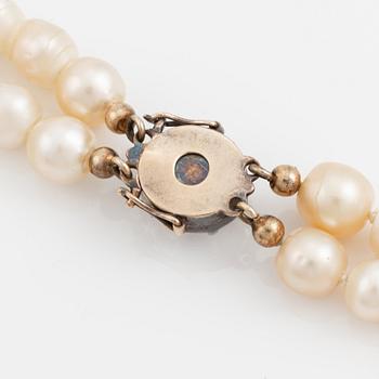 A two strand natural pearl necklace with a silver  clasp set with an old-cut diamond.