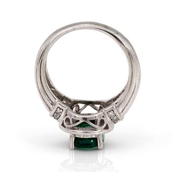 A ring with an oval, mixed-cut emerald and diamonds.