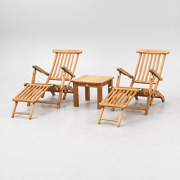 A pair of teak deck chairs and a table, 21st Century.