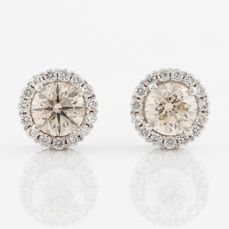 A pair of 18K gold earrings with round brilliant-cut diamonds.