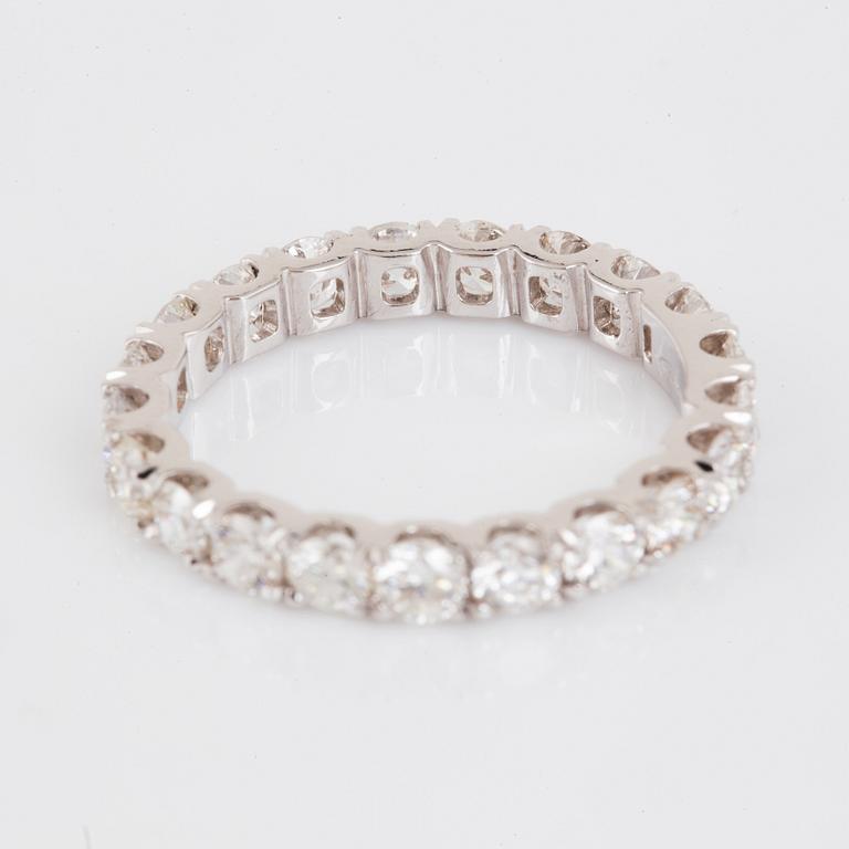 An 18K gold eternity ring set with round brilliant-cut diamonds.