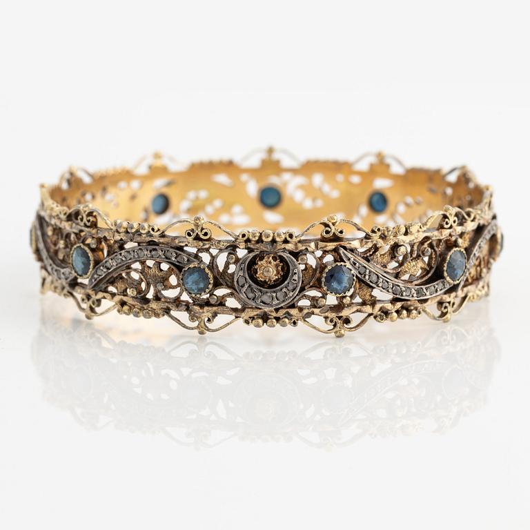 Bangle 18K gold and silver with rose-cut diamonds and blue stones, possibly sapphires.