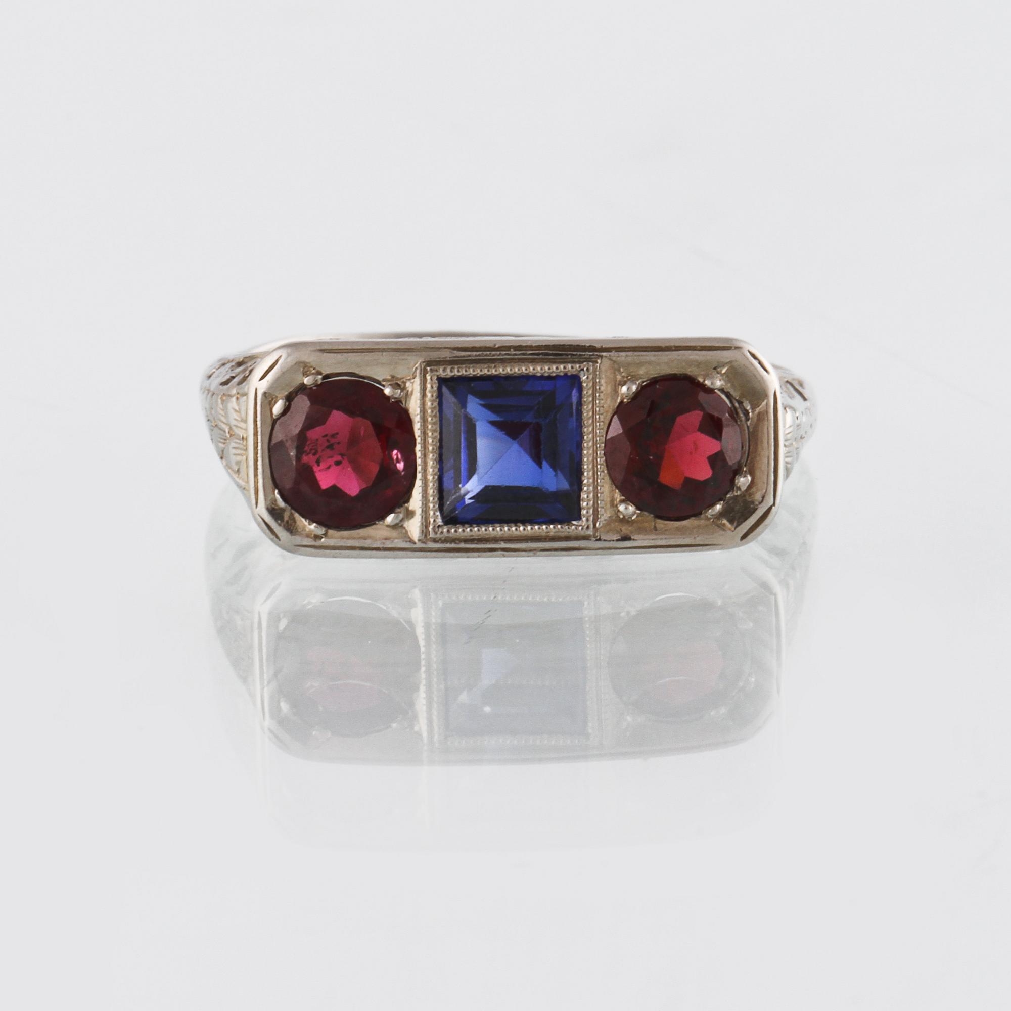 RING, 18K vitguld med fasettslipad blå safir samt 2 fasettslipade granater, utländska stämplar. Vikt 3,6 gram.