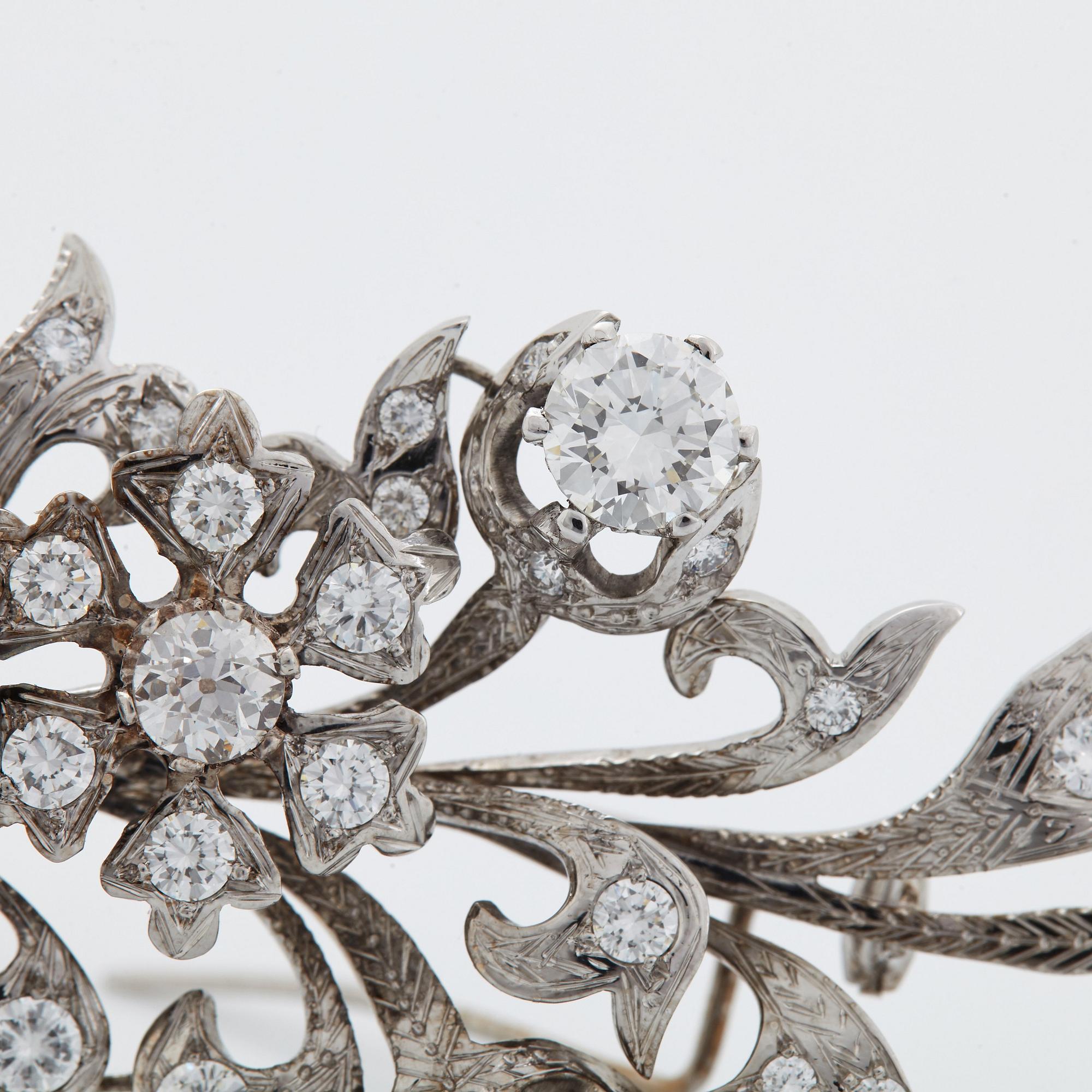 An 18K white gold brooch set with round brilliant-cut diamonds.