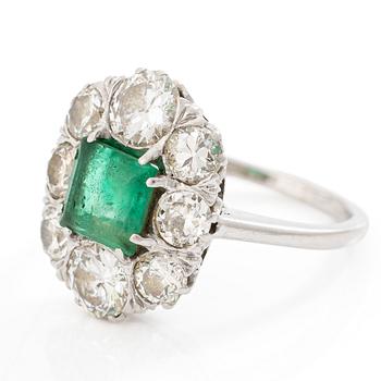 18K white gold ring set with a faceted emerald and round brilliant-cut diamonds.