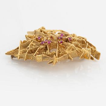 An 18K gold brooch set with faceted rubies.