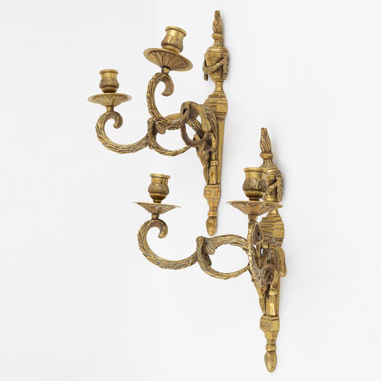 A pair of brass Louis XVI-style two-light wall lights, early 20th Century.