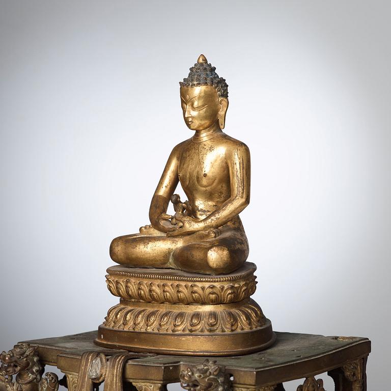 A large Nepalese gilt bronze buddha on a throne with mandorla, 18/19th Century.