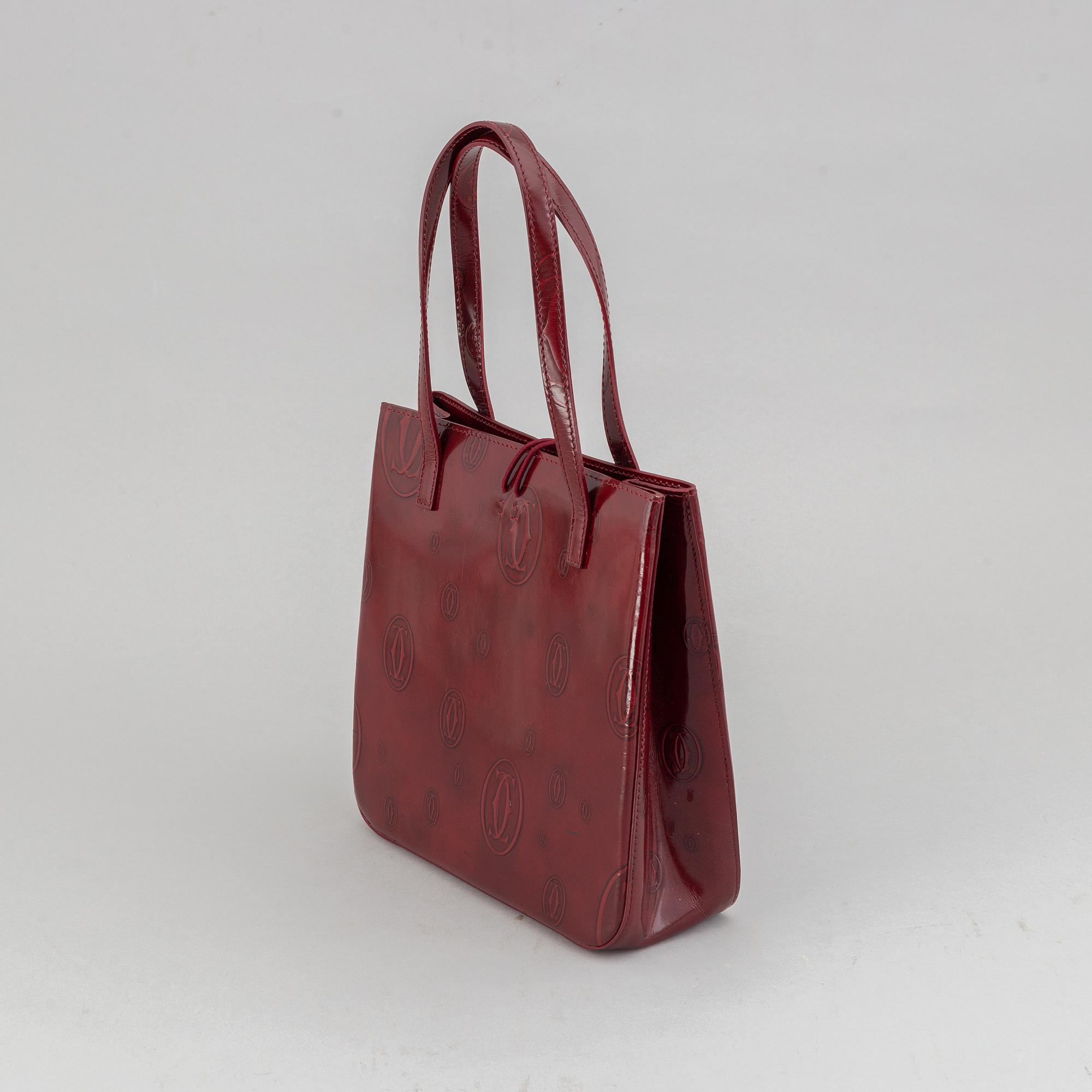 Cartier, a burgundy patent leather handbag and wallet.