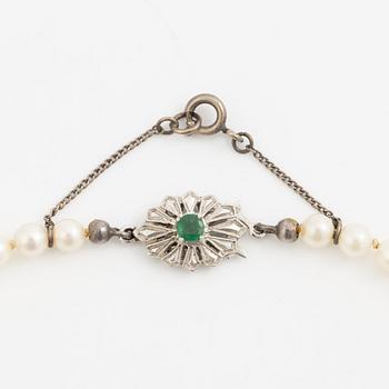 Necklace with graduated cultured pearls, with a clasp in 18K white gold set with an emerald.