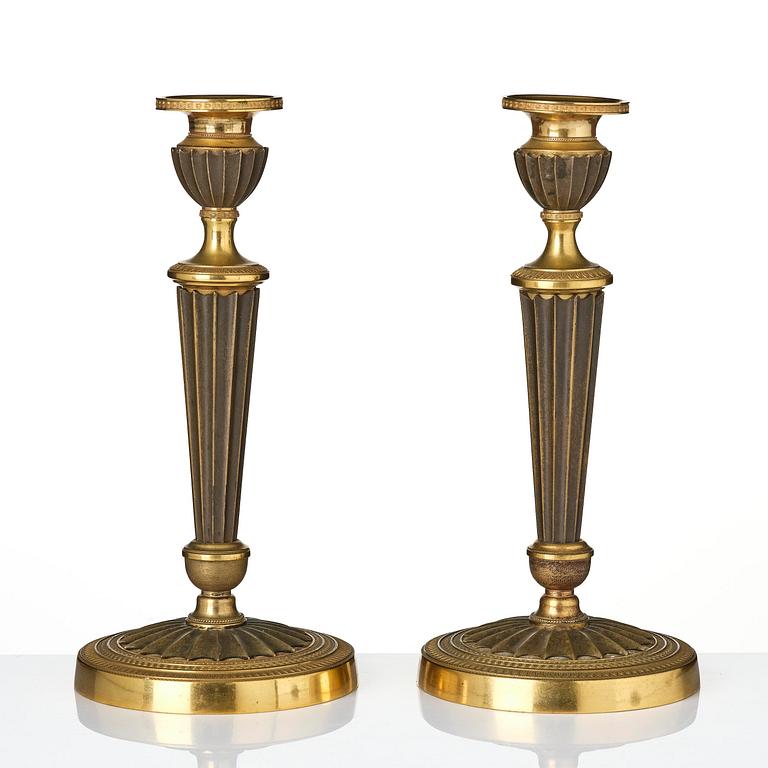 A pair of French Empire patinated and ormolu candlesticks, early 19th century.
