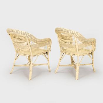 A mid-20th-century three-piece rattan furniture set including two armchairs, and a table.