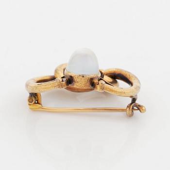 A 14K gold brooch set with a cabochon-cut moonstone and a pink sapphire.