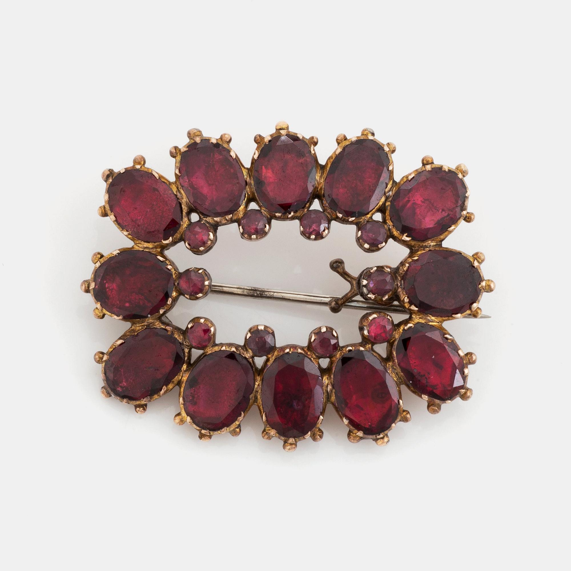 A silver and gold brooch set with faceted garnets.