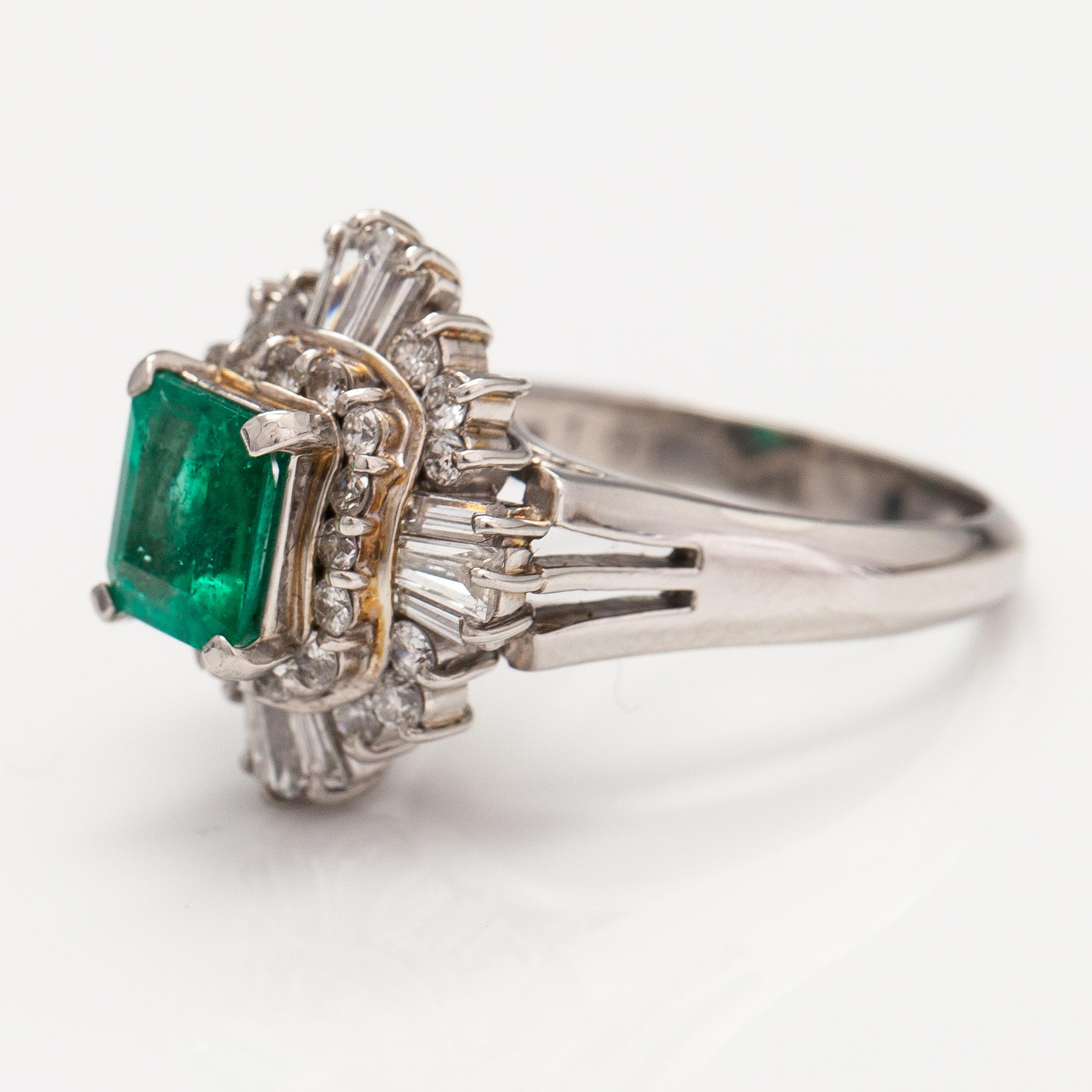 A platinum ring with a ca. 1.15 ct emerald and ca. 1.00 cts of diamonds in total.