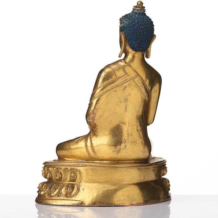 A gilt copper alloy figure of Akhsobya buddha, Tibet, 15th Century.