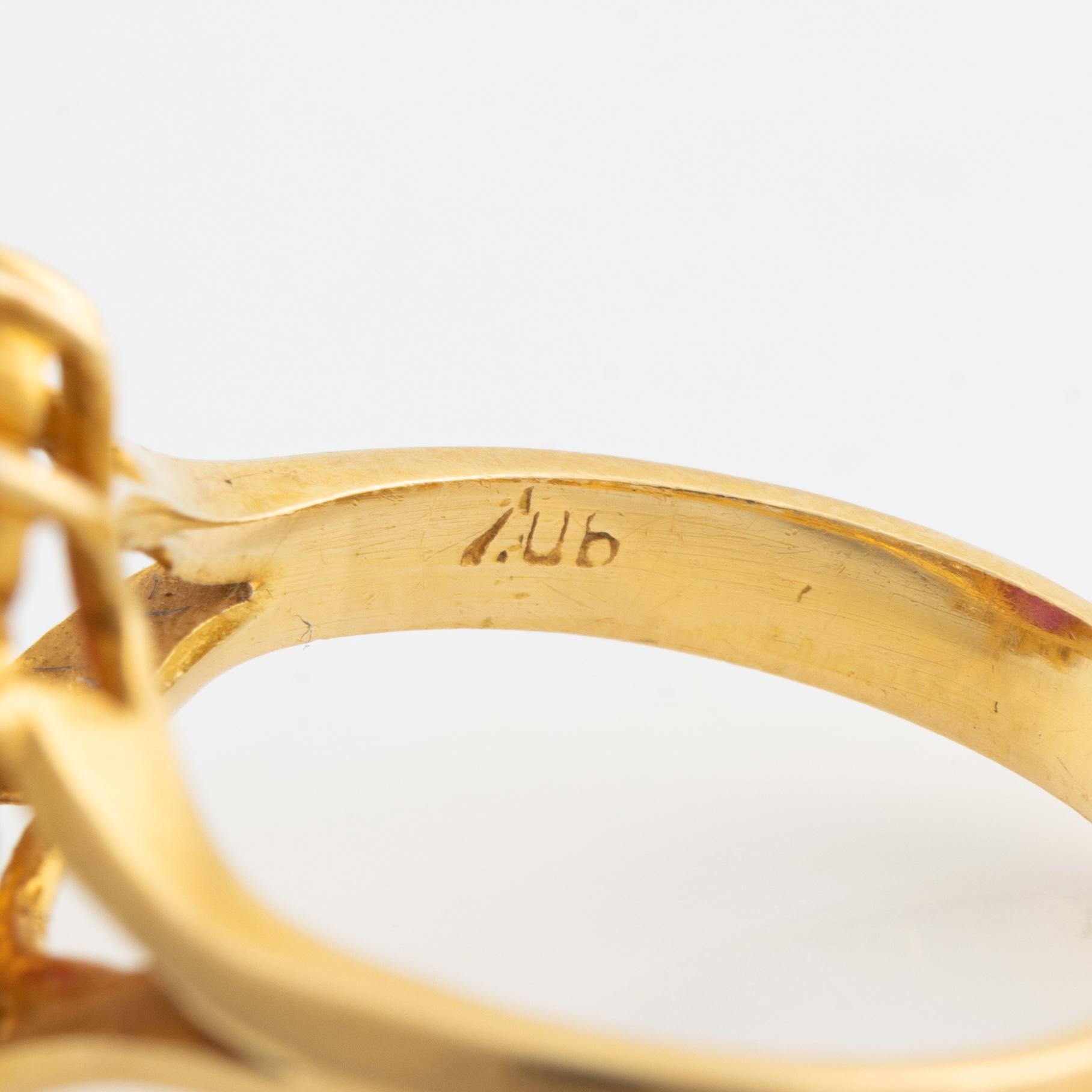 An 18K gold ring set with a cabochon-cut ruby and round brilliant-cut diamonds.