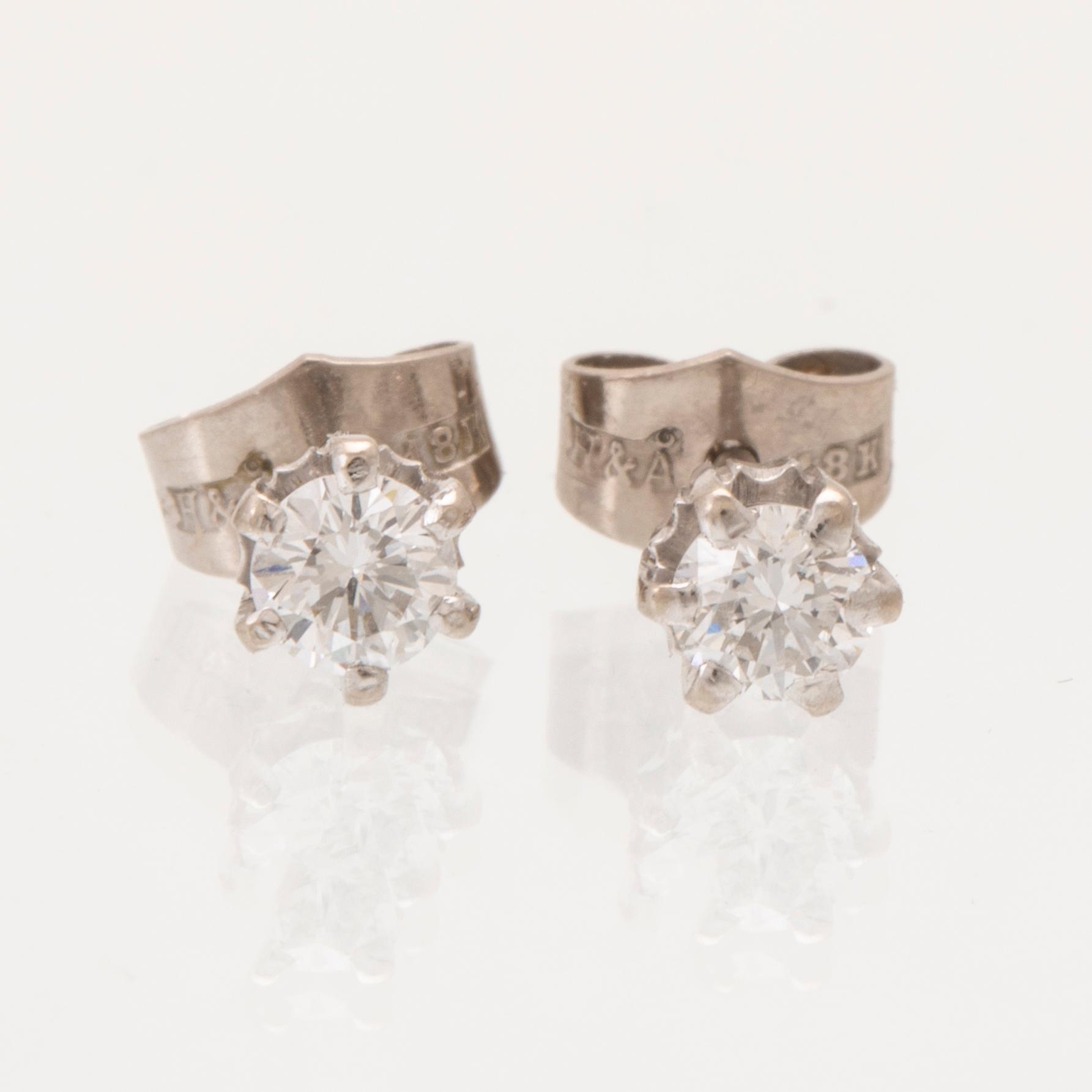 A pair of 18K white gold earrings set with round brilliant cut diamonds.