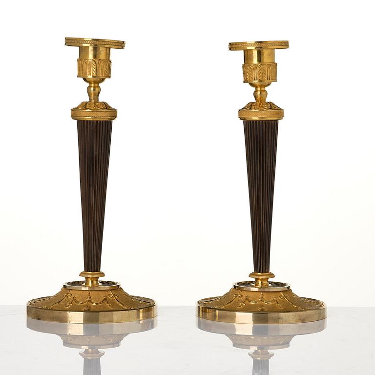 A pair of Empire ormolu and patinated bronze candlesticks.