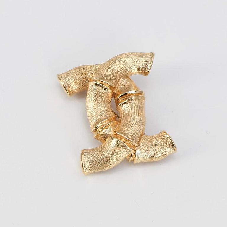 CHANEL, a gold colored brooch.