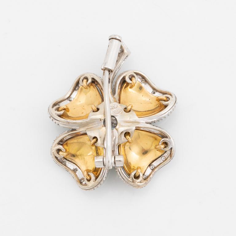 An 18K gold and enamel brooch set with round brilliant-cut diamonds.