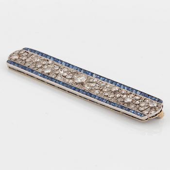 A platinum and gold brooch set with old- and rose-cut diamonds and faceted sapphires.