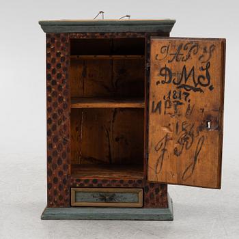 A painted wall cabinet, dated 1817.
