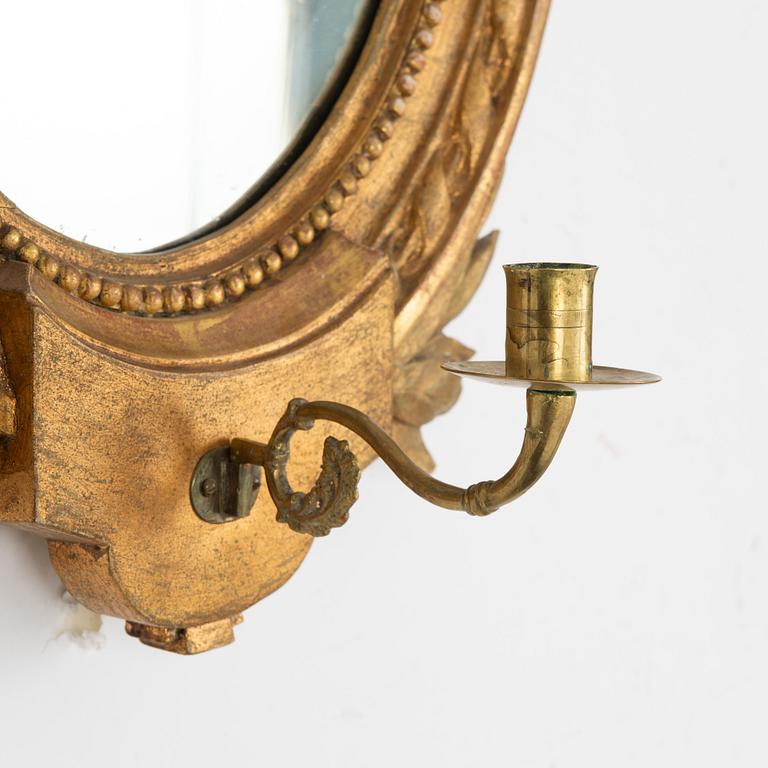 A Gustavian one-branch giltwood girandole mirror (with an associated copy), Stockholm, late 18th century.