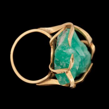 A gold ring set with an un-cut stone, probably emerald.