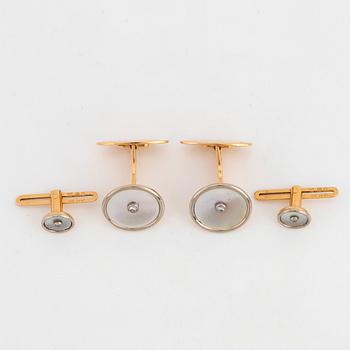 A pair of cufflinks and a pair of shirt buttons.