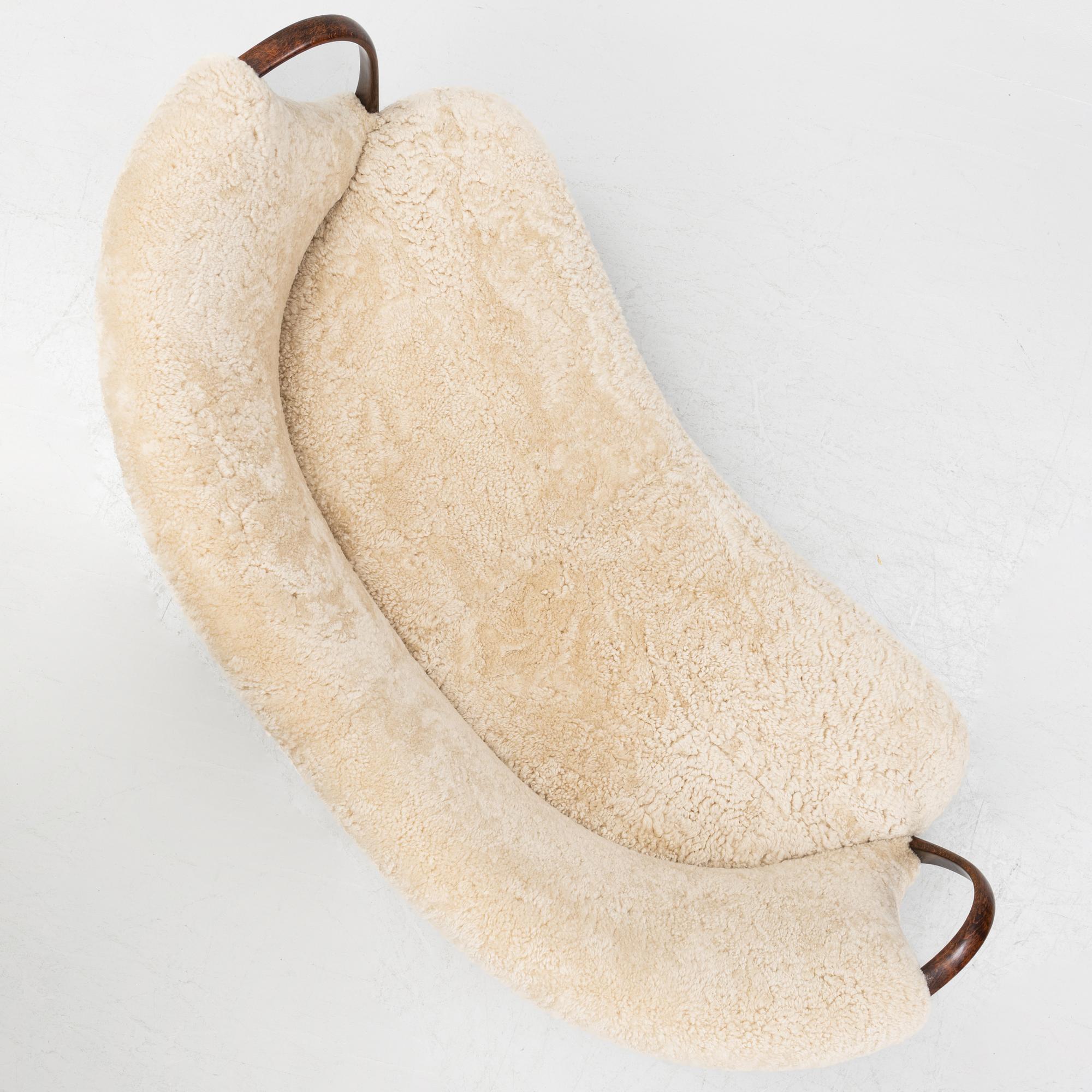 A curved sofa attributed to Viggo Boesen with new sheepskin upholstery and stained beech tree armrests.
