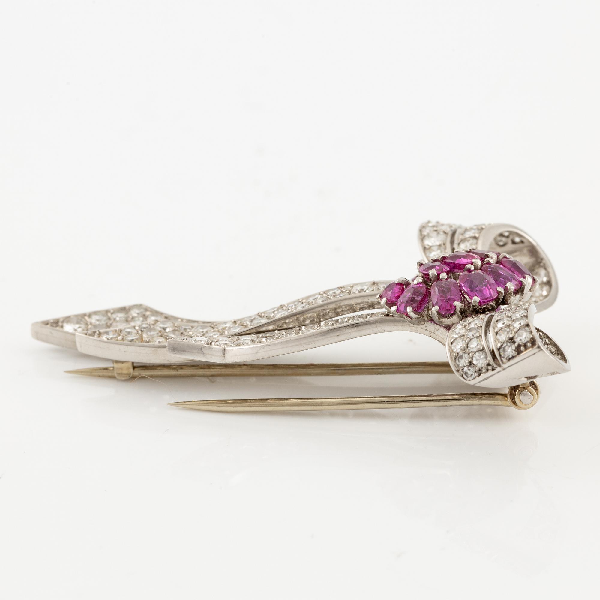 A brooch in platinum in the form of a bow with rubies and diamonds, likely from the 1950s.