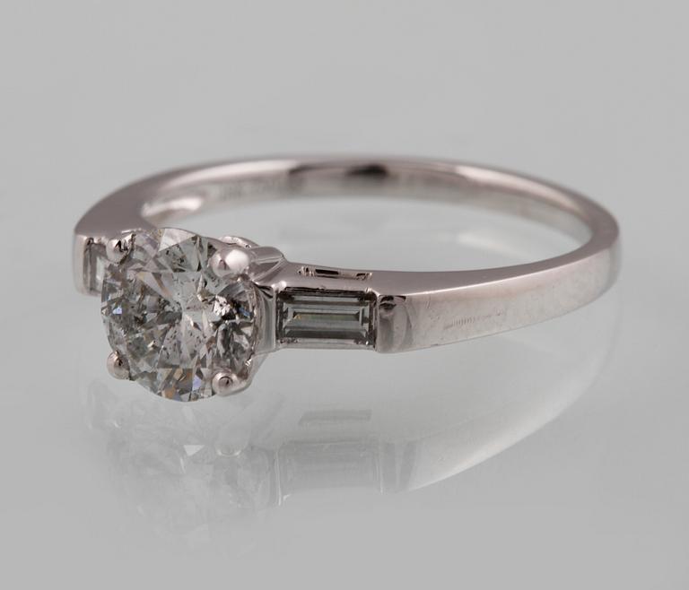 RING, 18K vitguld med briljantslipad diamant ca 1.05 ct samt 2 baguettslipade diamanter ca 0.17 ct. Vikt 3,2 gram.