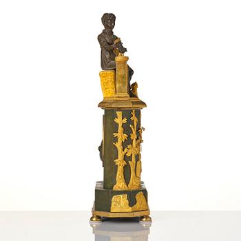 A French patinated and ormolu Directoire figural mantel clock, circa 1800.