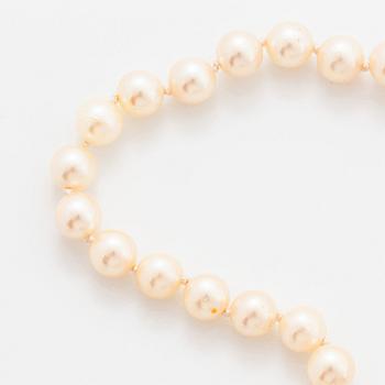 A cultured pearl necklace with a bow clasp in 18K gold set with round brilliant-cut diamonds.