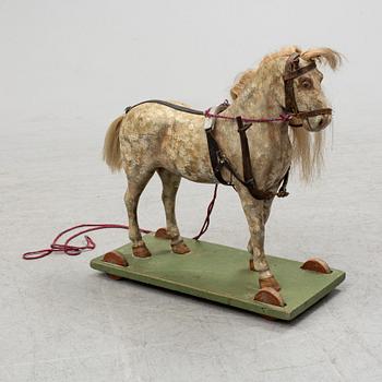 A painted early 20th century toy horse on wheels.