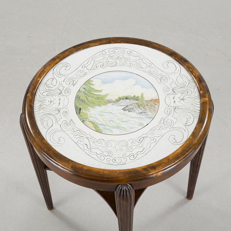 A table from the first halft of the 20th century with a "Kalmar Fajans" tabletop, painted by John Sjöstrand.