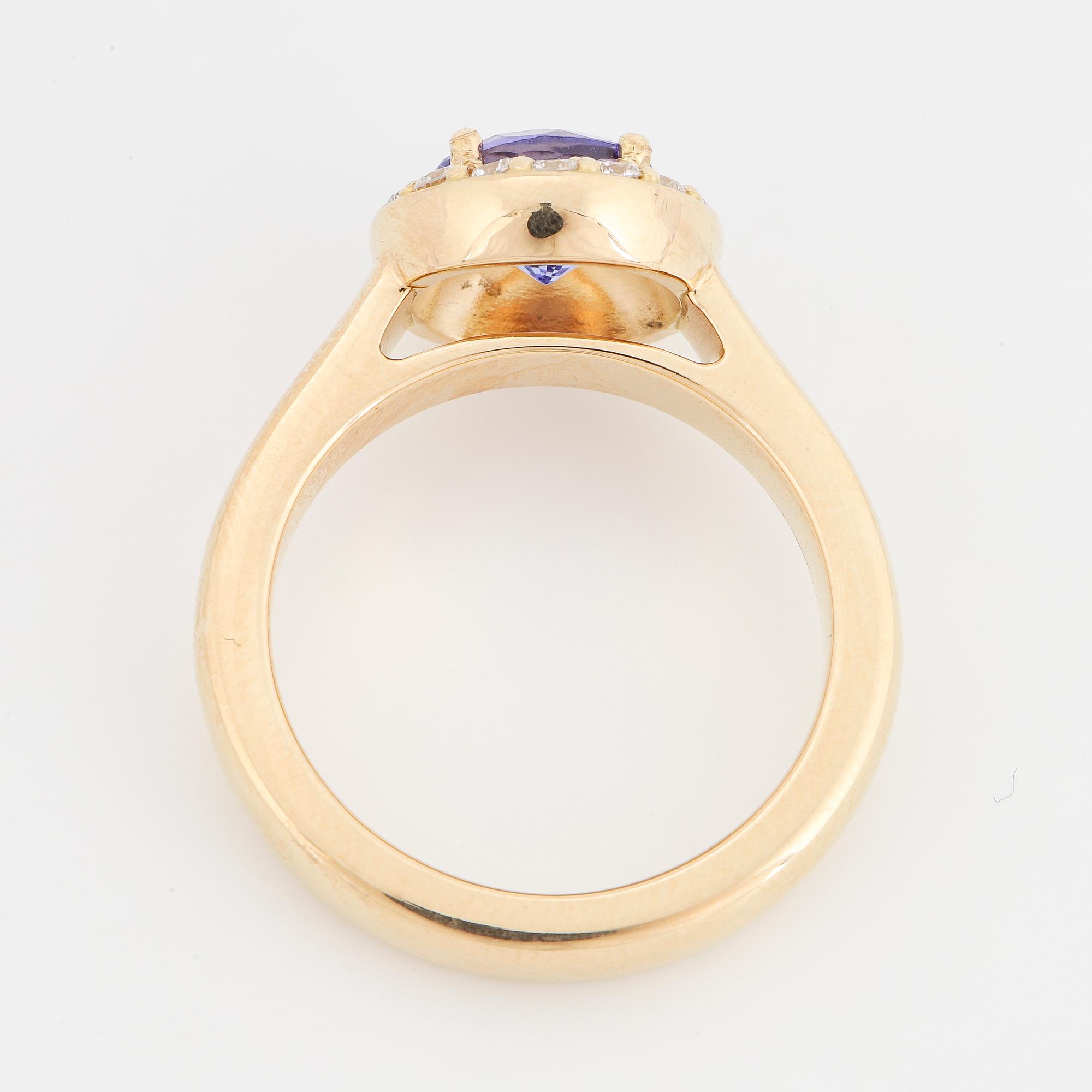 An 18K gold ring set with a faceted tanzanite and round brilliant-cut diamonds.