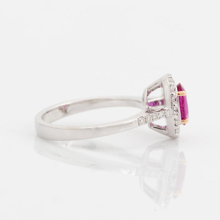 An 18K white gold ring set with a faceted pink sapphire and round brilliant-cut diamonds.