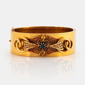 996. An 18K gold bangle set with a faceted sapphire.