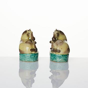 A pair of green, yellow and aubergine glazed biscuit figures of recumbent horses, Qing dynasty.
