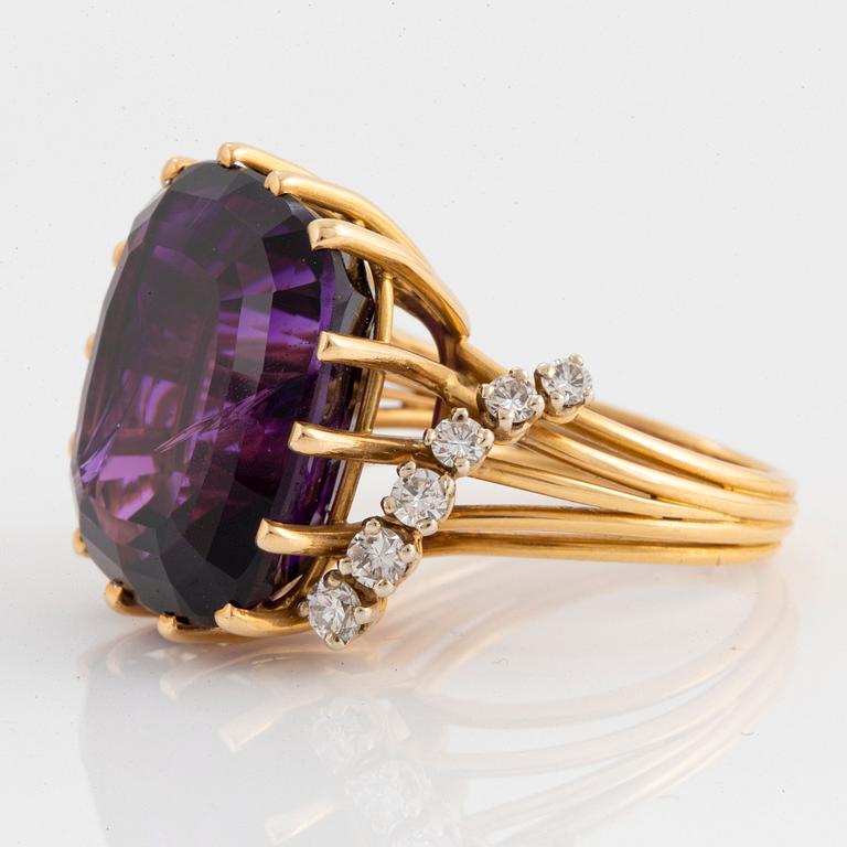 An 18K gold ring set with a faceted amethyst and round brilliant-cut diamonds.